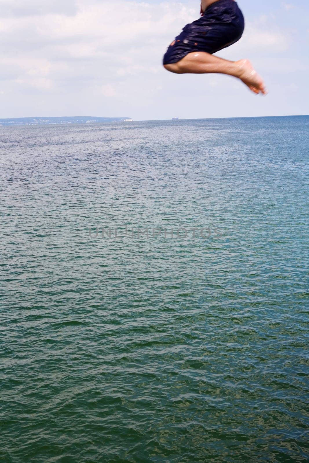 A young man jumps into the water,only the legs can be seen in motion blur