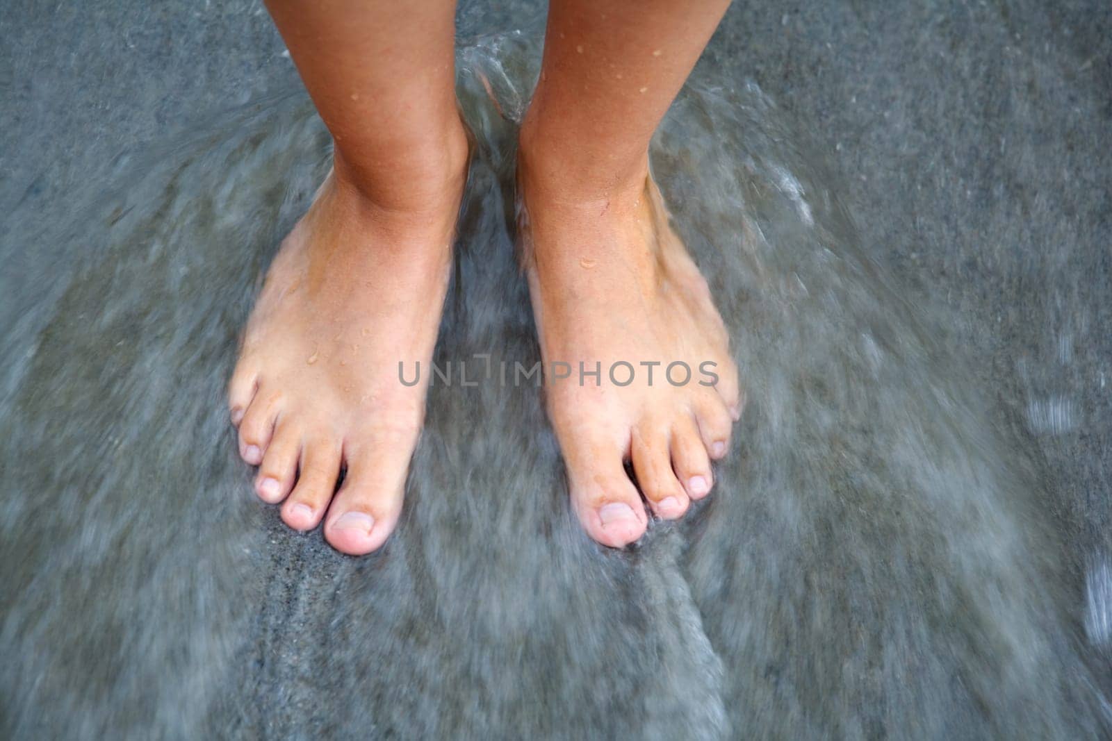 Women's feet in the sea washed by water