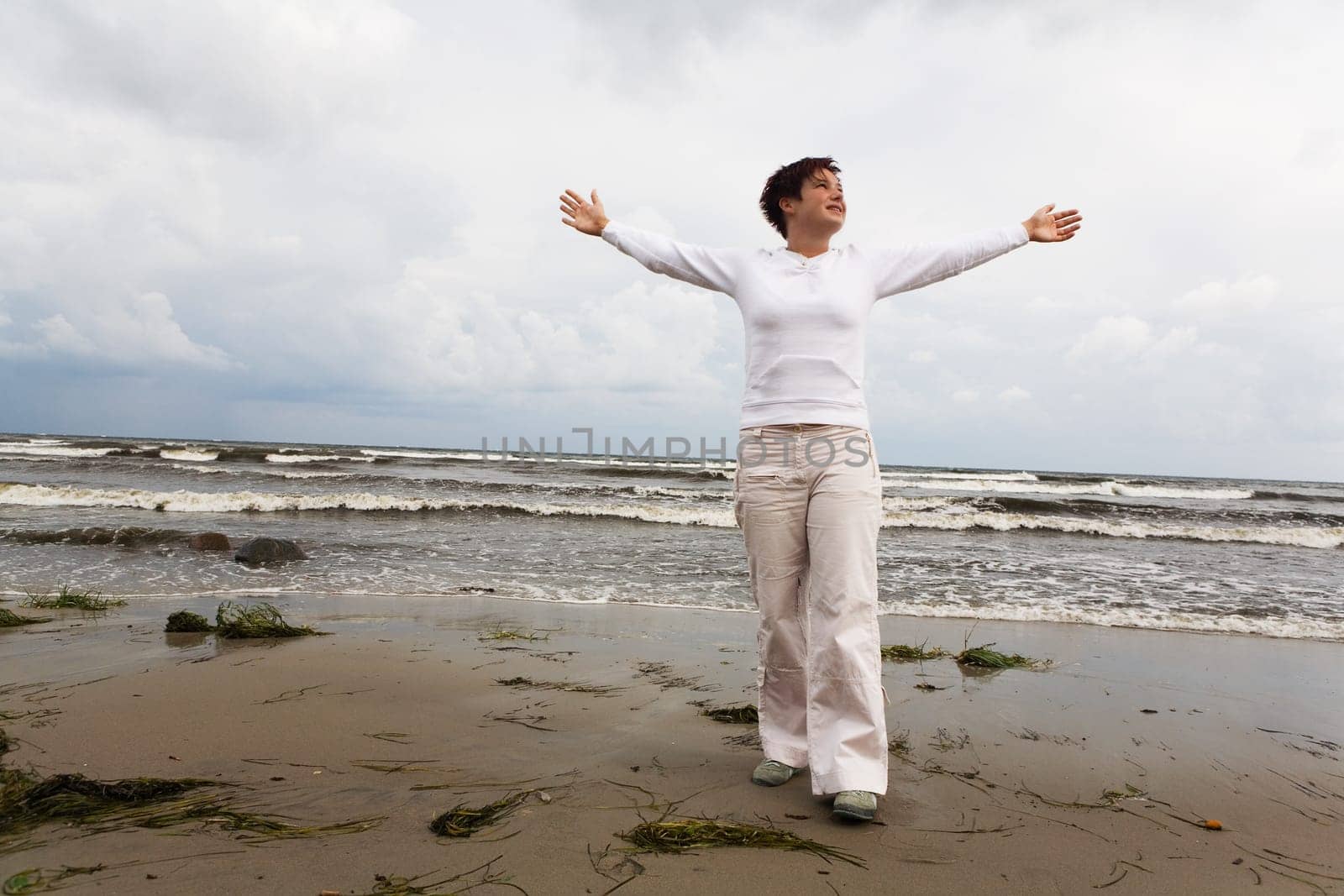 A teenager stands with outstretched arms on the beach