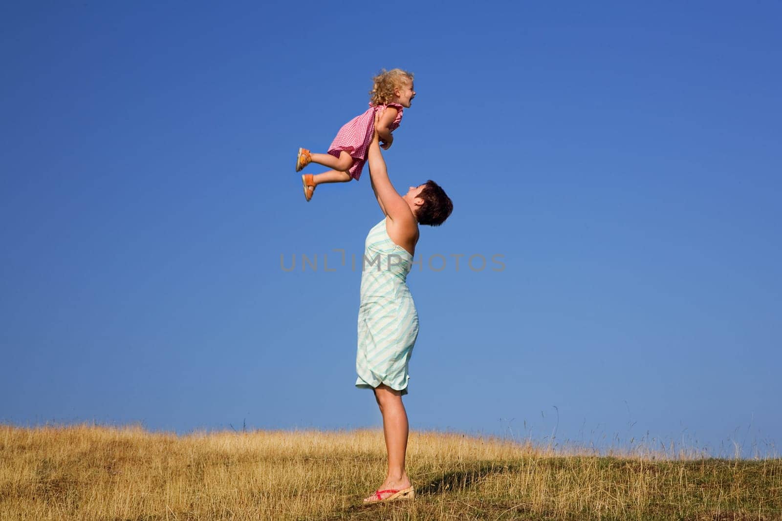 A young girl and a toddler,the toddler is lifted up
