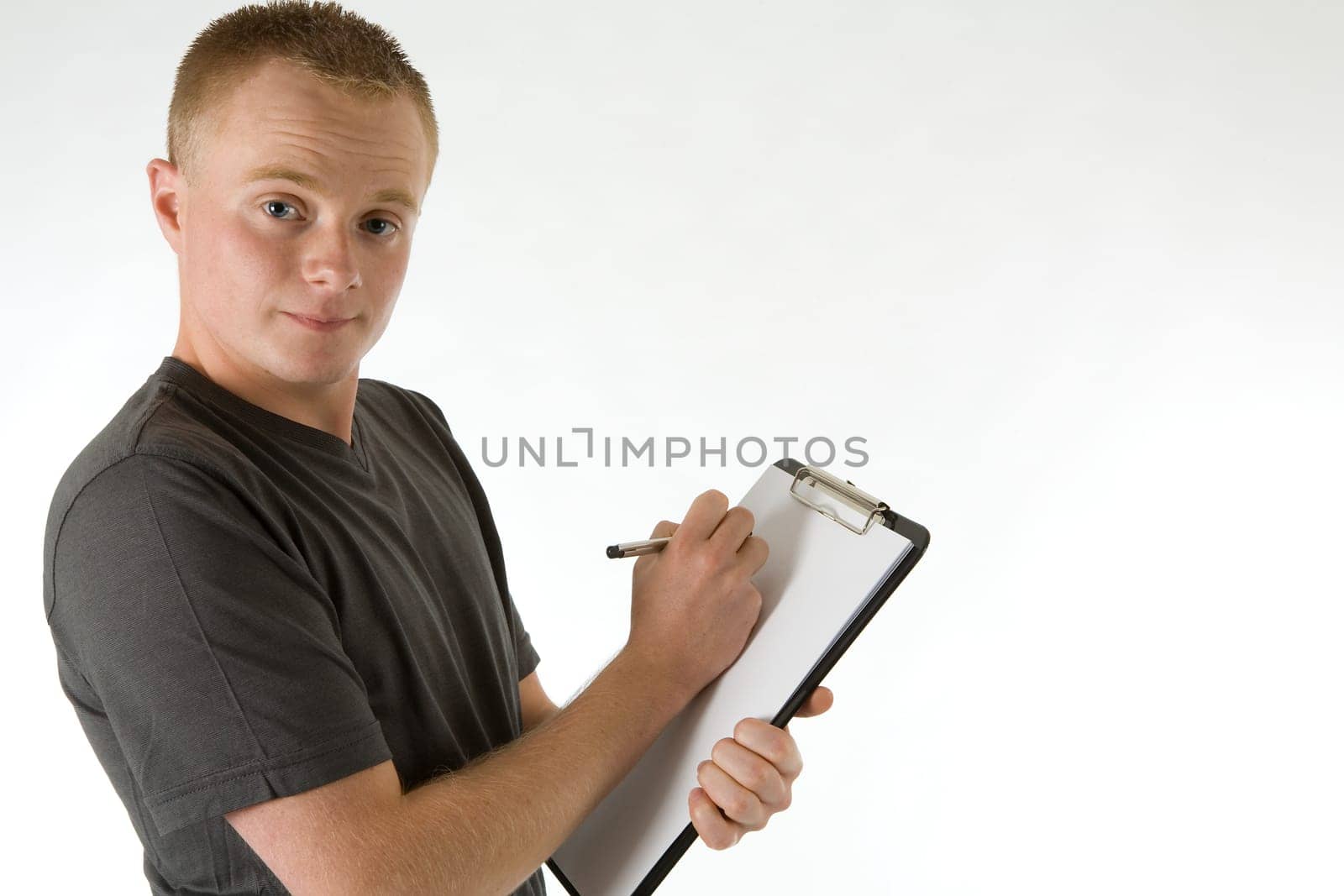 A young man holds a paper clipboard (white sheet for his own text) and a pen in his hands