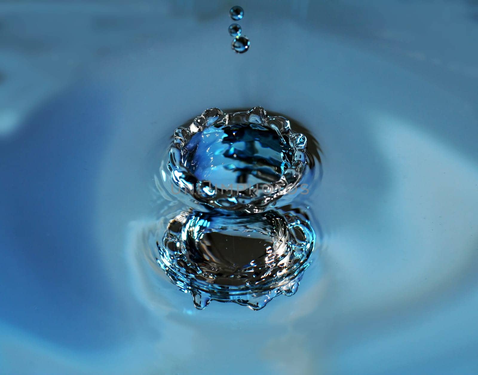 Impact of a drop on the surface of the water from above and seen from below at the same time by reflection (negative form)