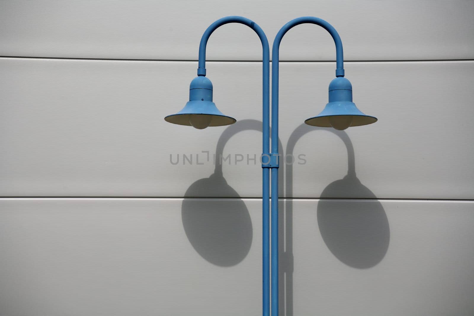 Blue street lamp in front of a house wall
