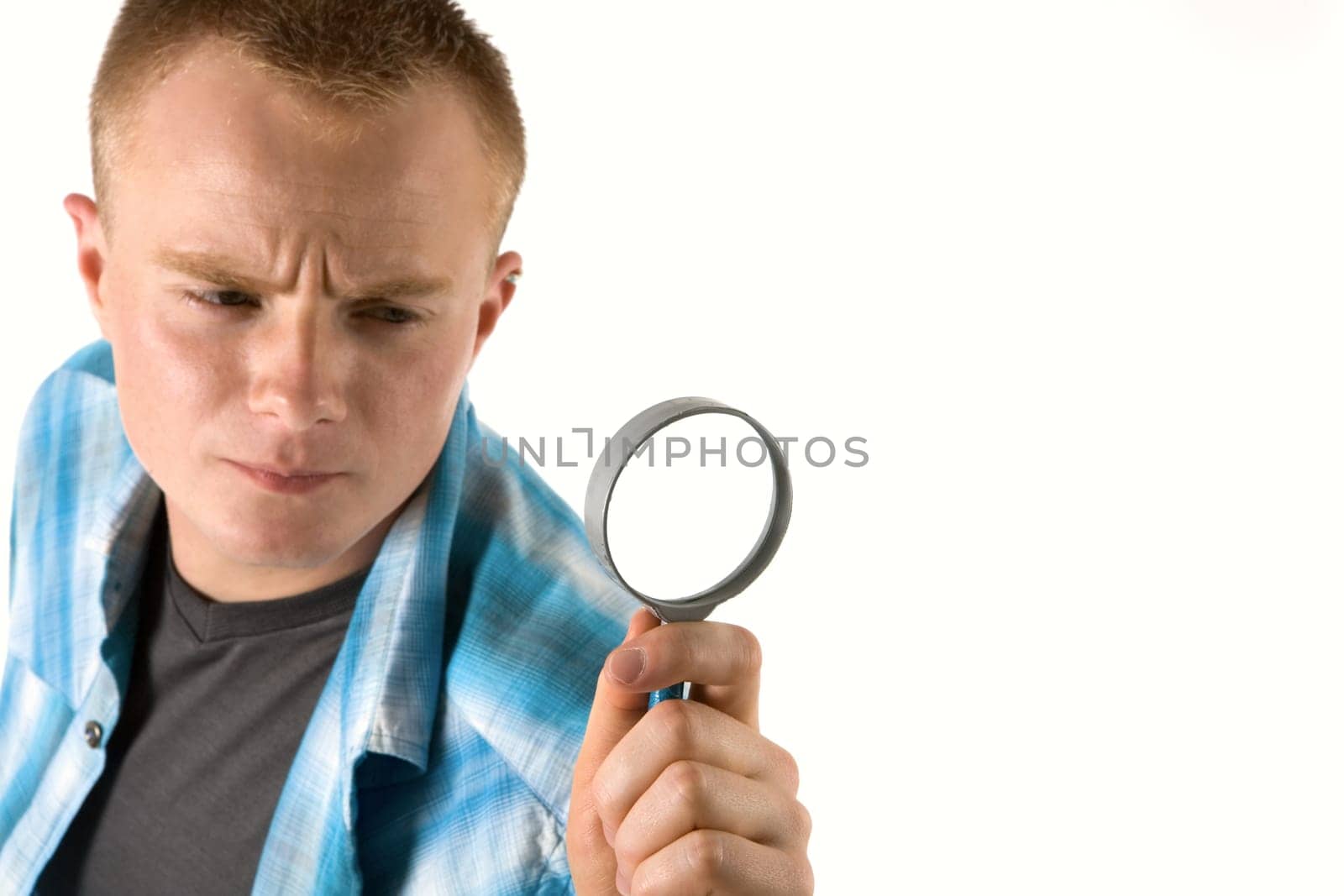 A young man looks through a magnifying glass