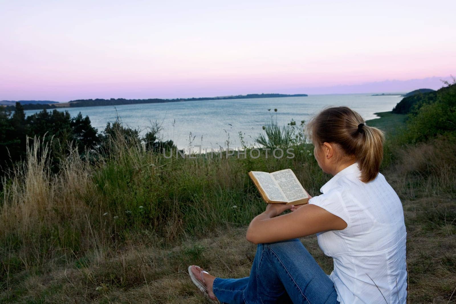 A young Faru sits in the grass and reads a book