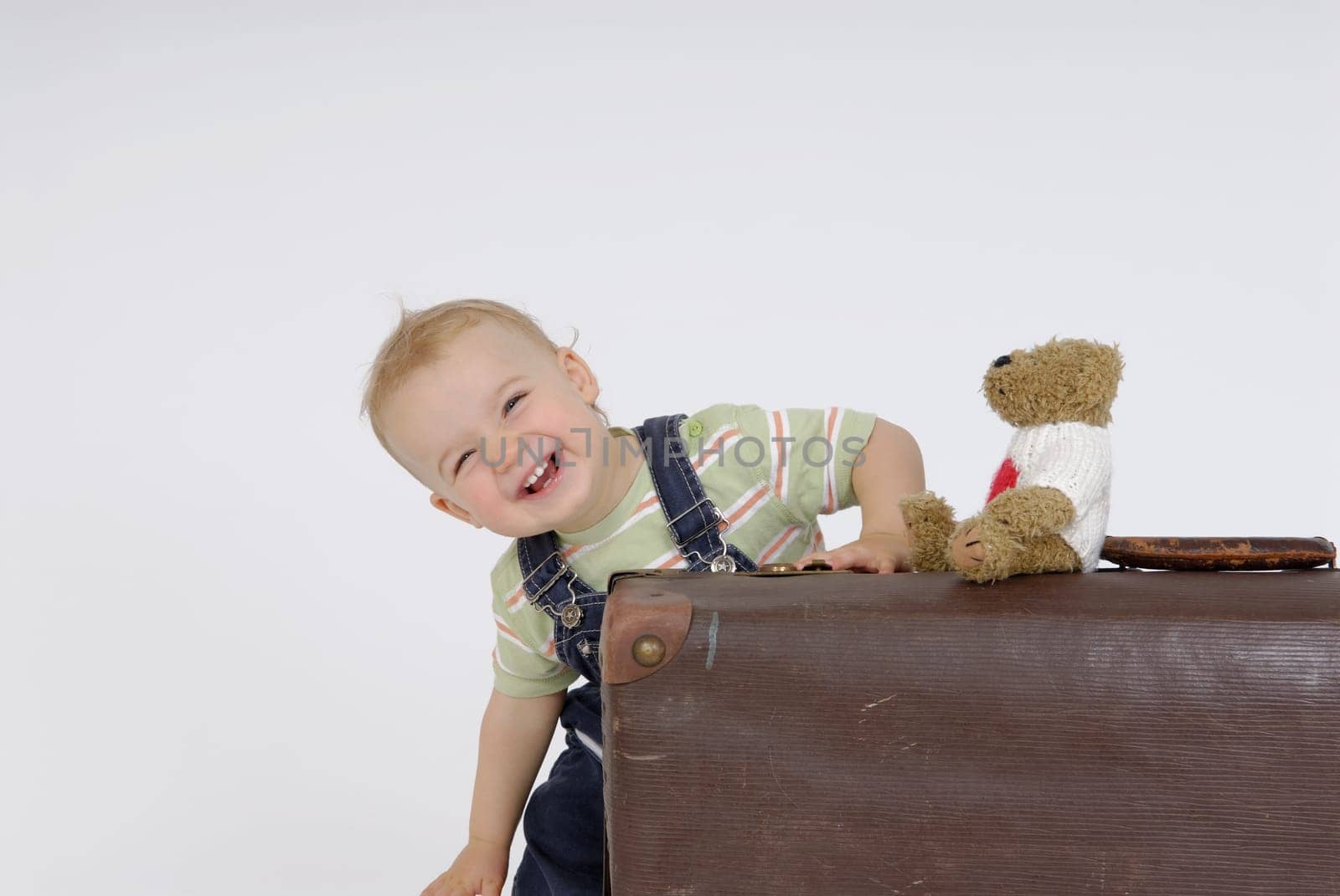 Toddler with suitcase and teddy bear. Studio recording