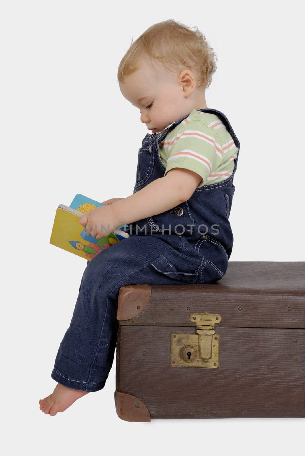 Toddler on suitcase with reading book. Studio recording