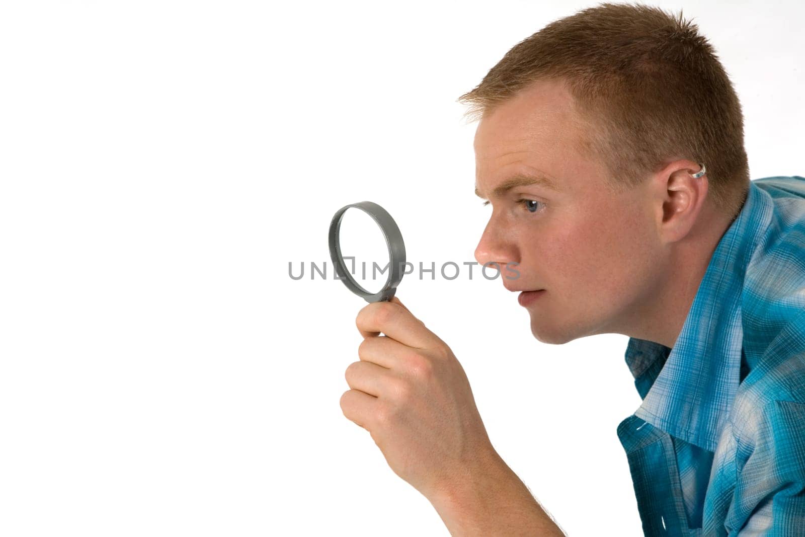 A young man looks through a magnifying glass
