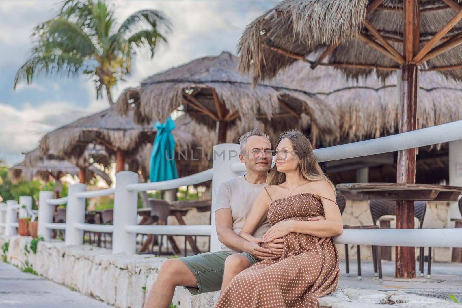 A happy, mature couple over 40, enjoying a leisurely walk in a park, their joy evident as they embrace the journey of pregnancy later in life by galitskaya