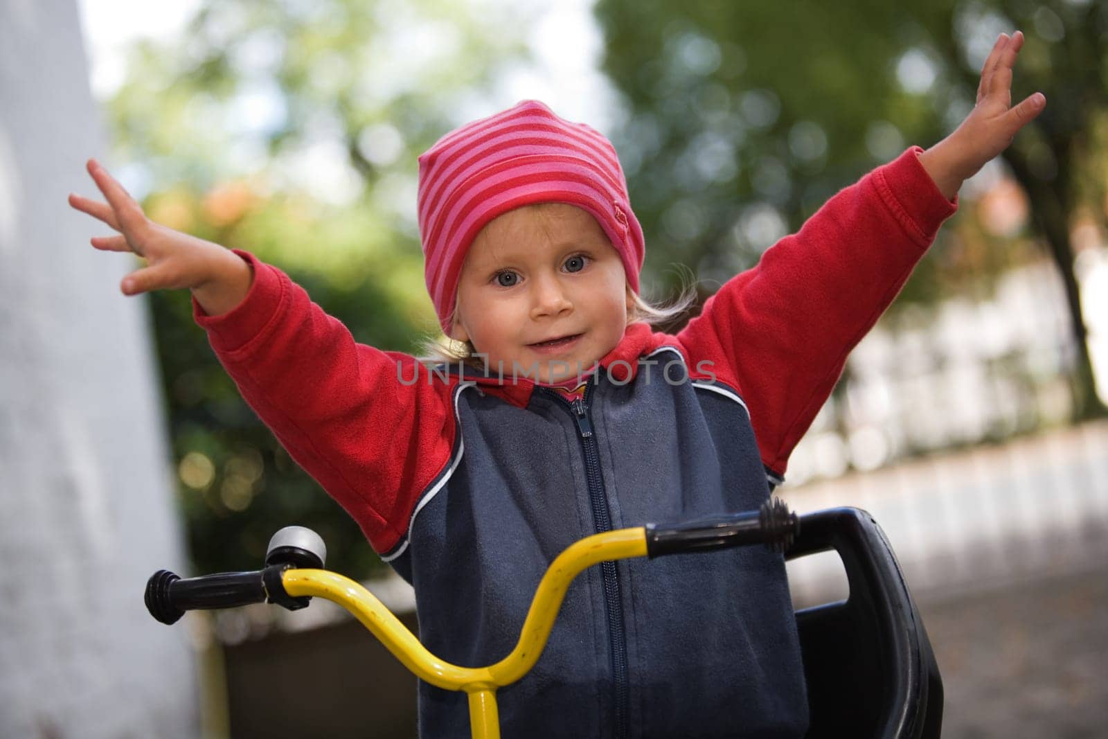 A little girl with outstretched arms and her bike