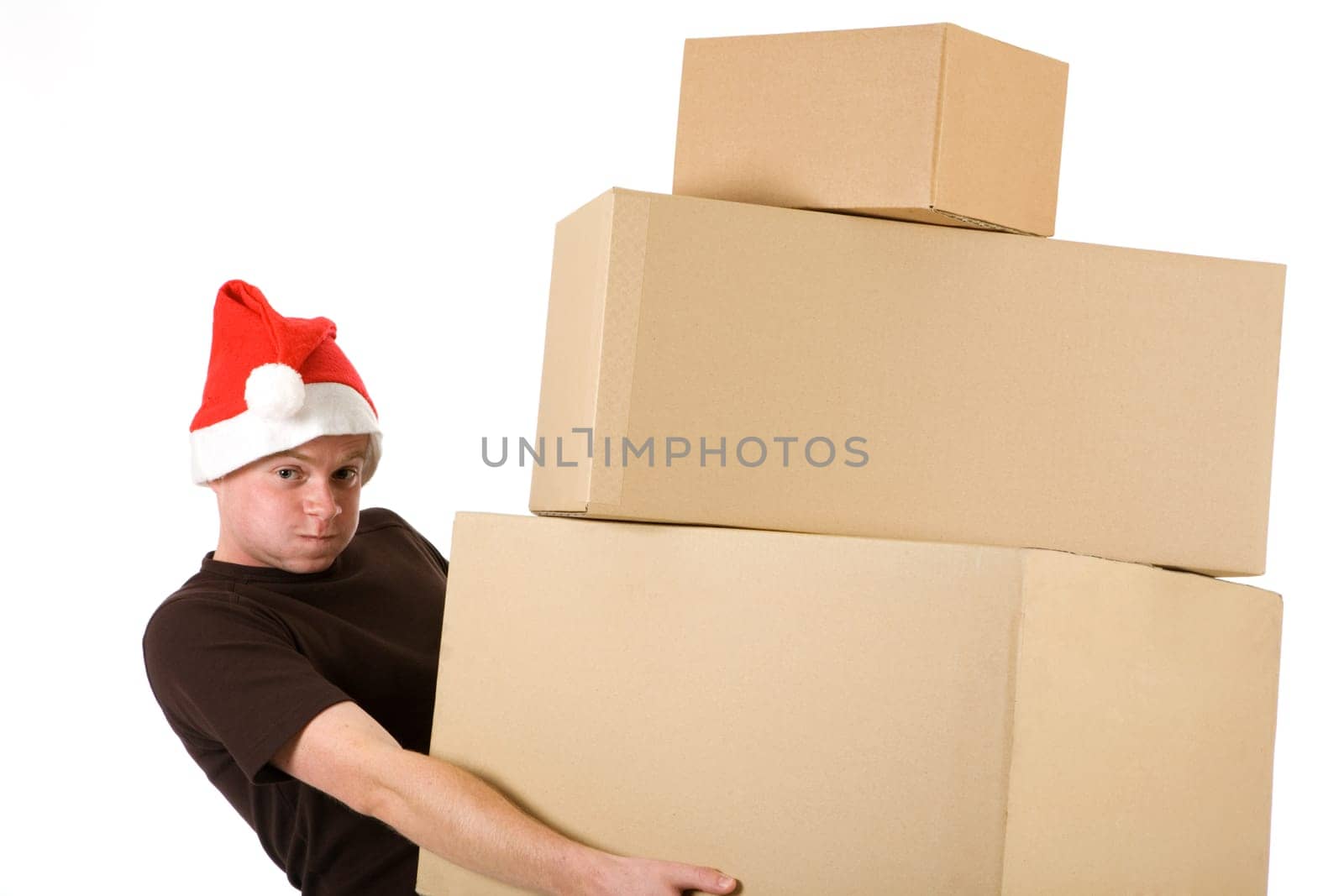 A man in a Santa Claus hat brings a stack of packages and looks strained