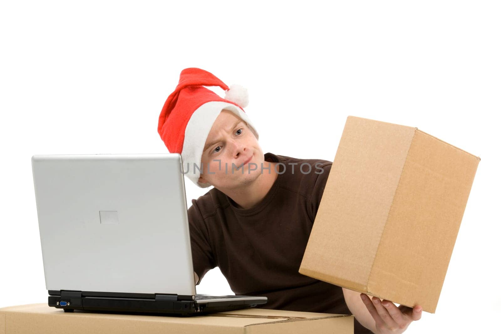 A man wearing a Santa Claus hat in front of a laptop with a package in his hand