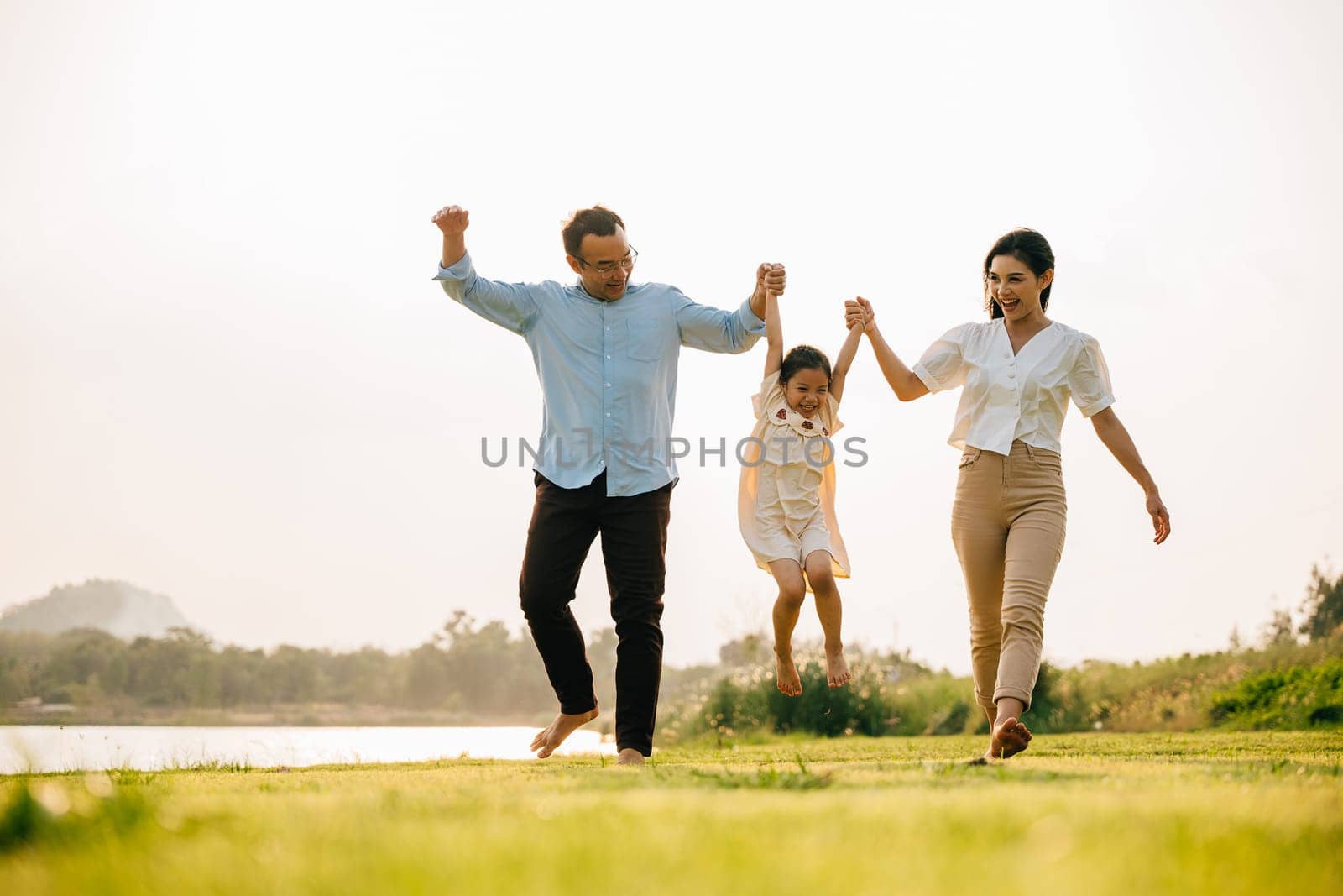Asian family walking and holding hands in a beautiful springtime park by Sorapop
