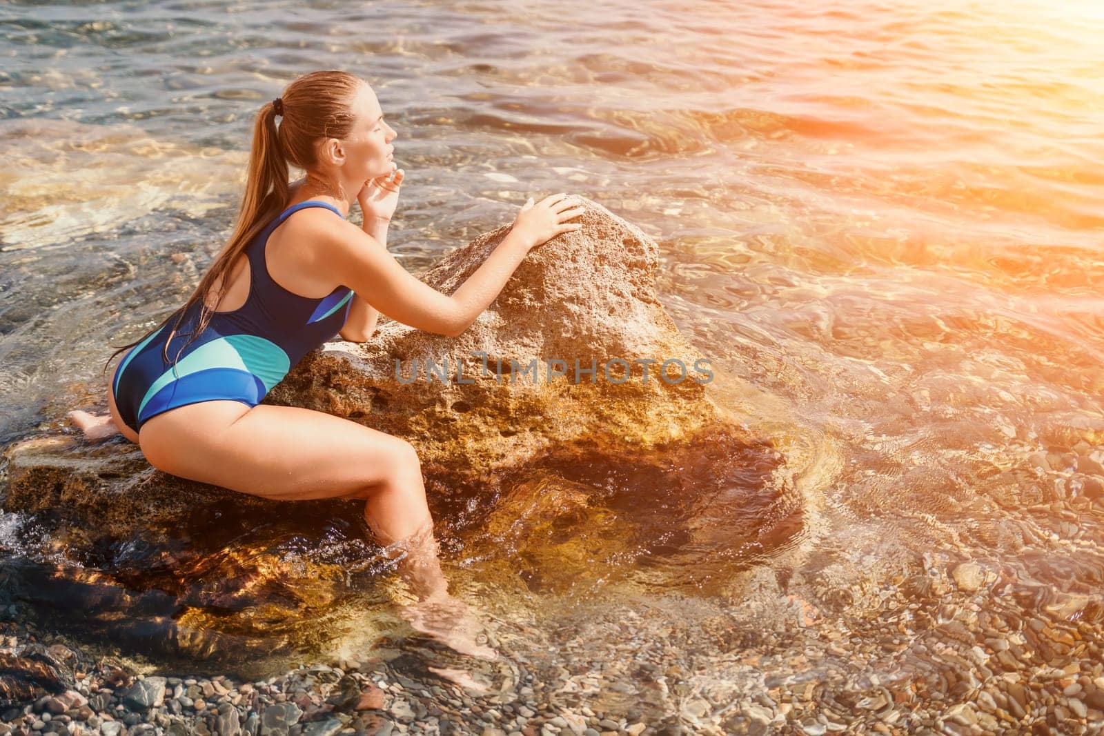 Woman travel sea. Happy tourist in blue swimwear takes a photo outdoors to capture memories. woman traveling and enjoying her surroundings on the beach, with volcanic mountains in the background. by panophotograph