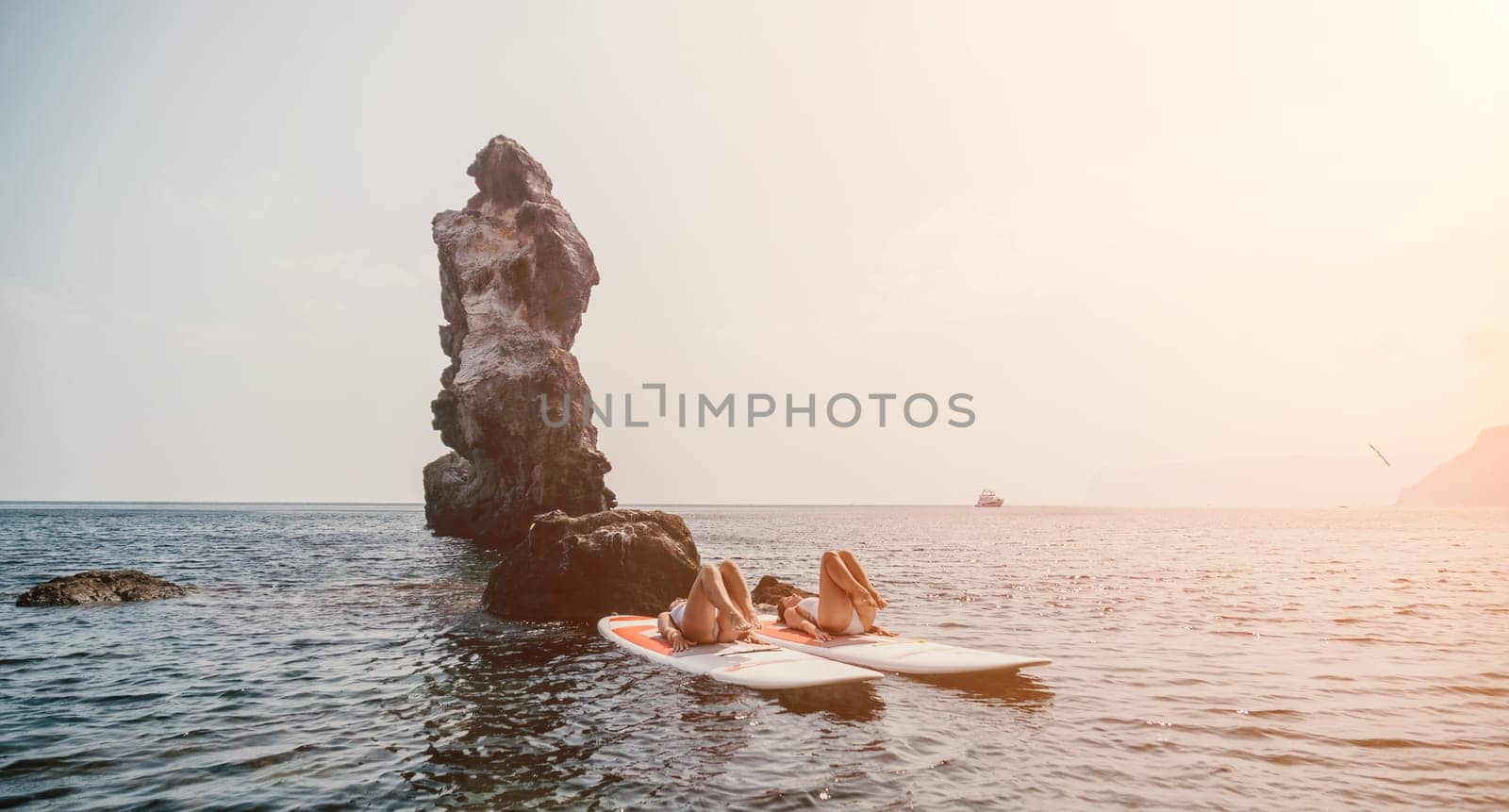 Woman sup yoga. Middle age sporty woman practising yoga pilates on paddle sup surfboard. Female stretching doing workout on sea water. Modern individual hipster outdoor summer sport activity