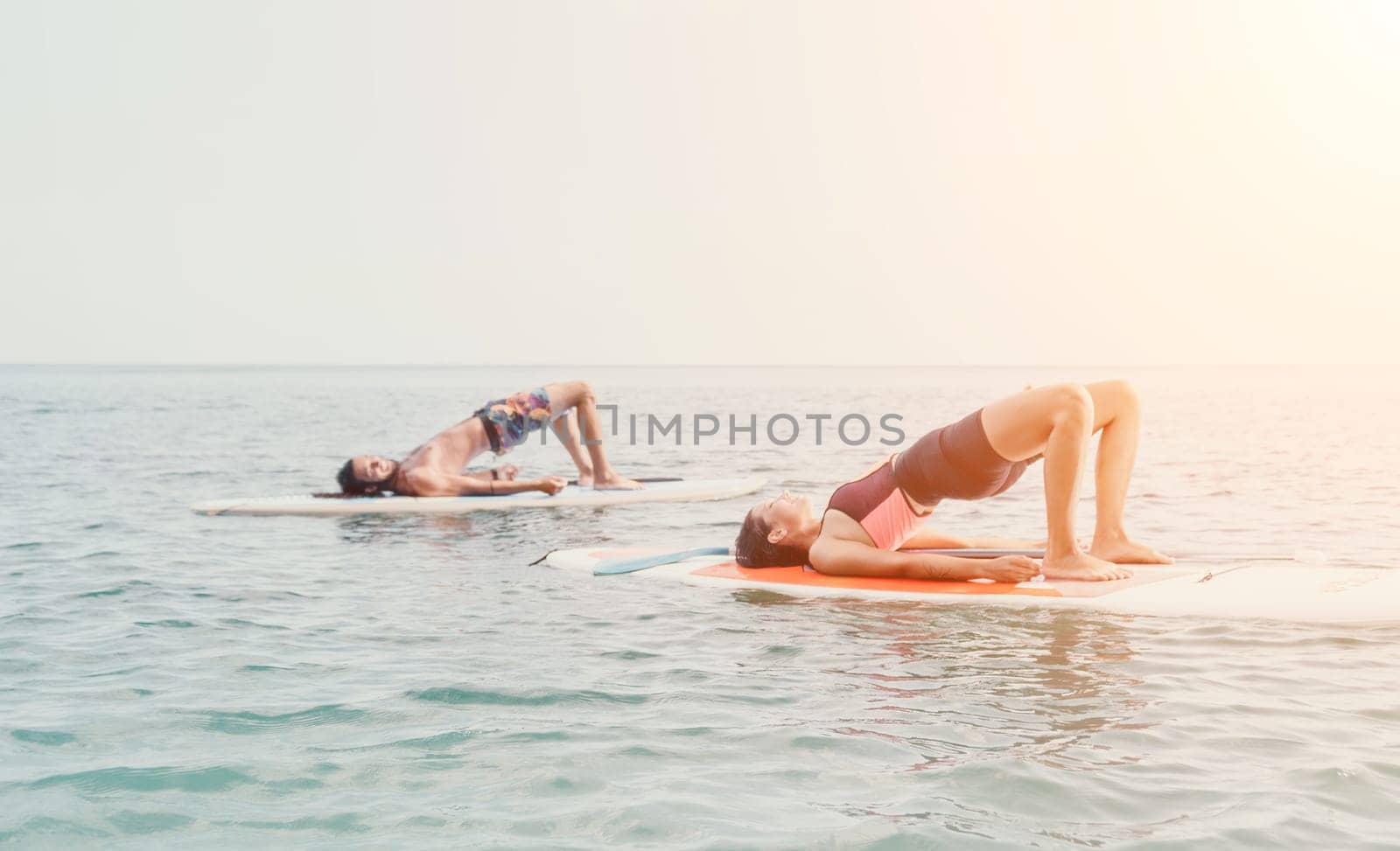 Woman sup yoga. Happy young sporty woman practising yoga pilates on paddle sup surfboard. Female stretching doing workout on sea water. Modern individual female outdoor summer sport activity