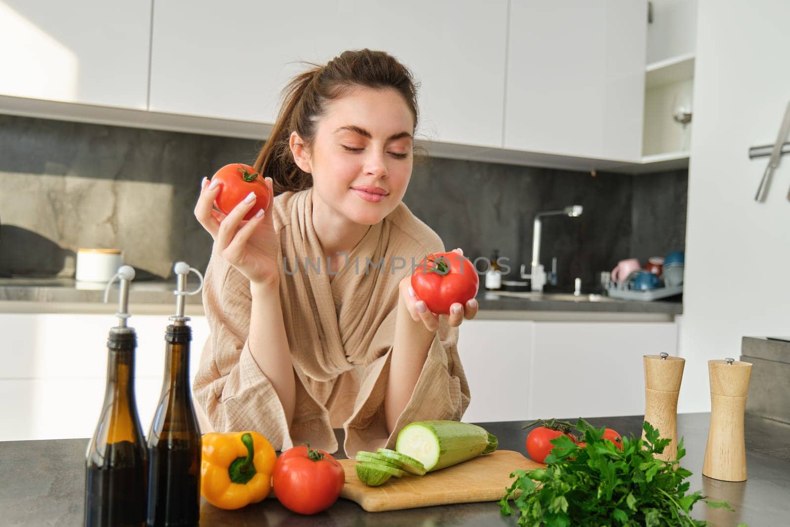 Portrait of woman cooking at home in the kitchen, holding tomatoes, preparing delicious fresh meal with vegetables, standing near chopping board by Benzoix