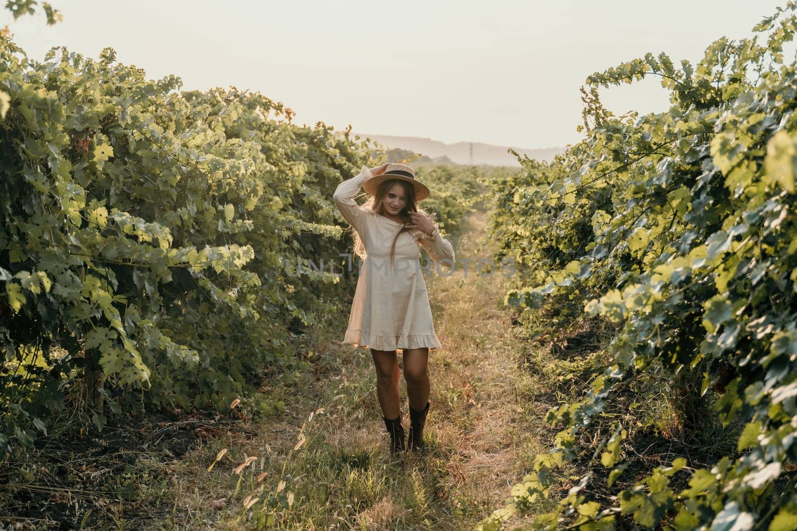 Woman at autumn winery. Portrait of happy woman holding glass of wine and enjoying in vineyard. Elegant young lady in hat toasting with wineglass smiling cheerfully enjoying her stay at vineyard