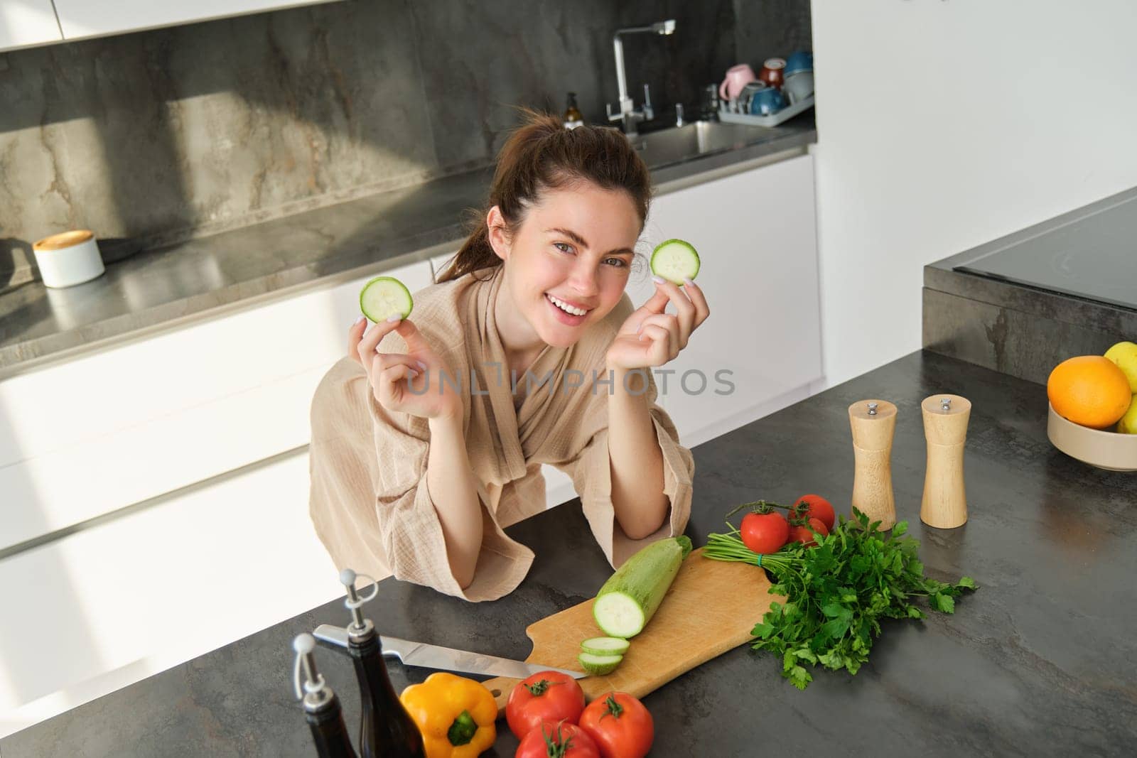 Portrait of good-looking woman cooking salad in the kitchen, chopping vegetables and smiling, preparing healthy meal, leading healthy lifestyle and eating raw food by Benzoix