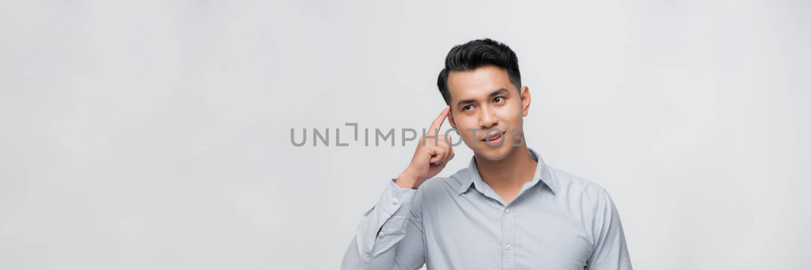 Young man point finger at his head gesture thinking portrait white background