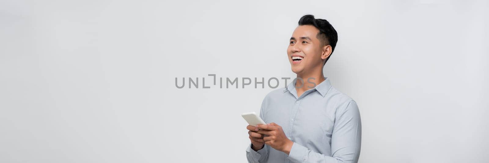 Young smiling handsome Asian man using mobile phone isolated on white background