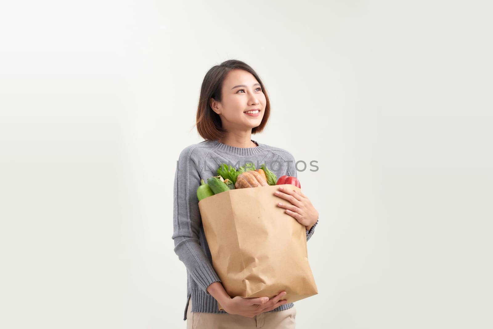 Young asian girl in sweater with groceries isolated.
