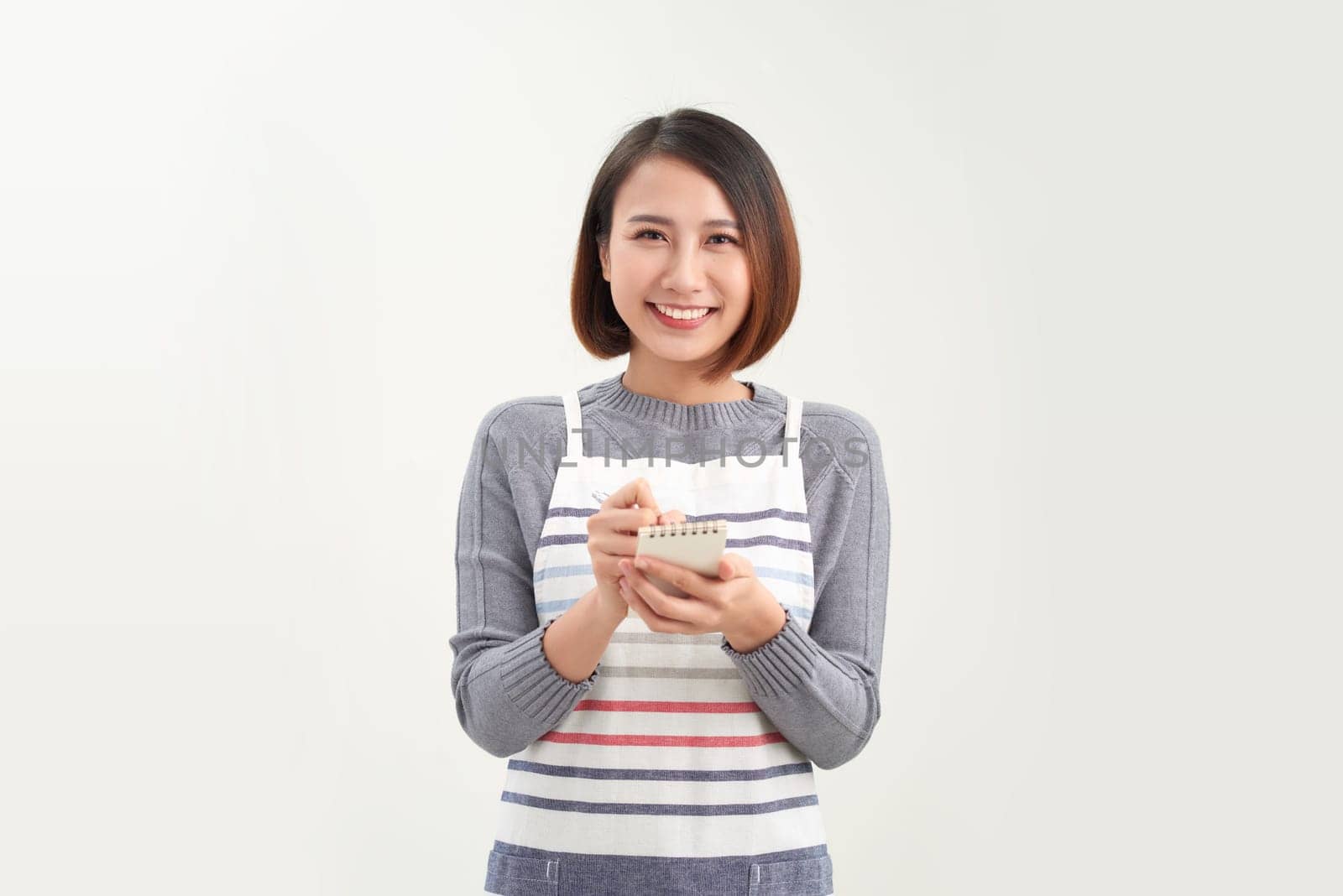 A young asian female waitress or barista taking an order on her tablet while smiling