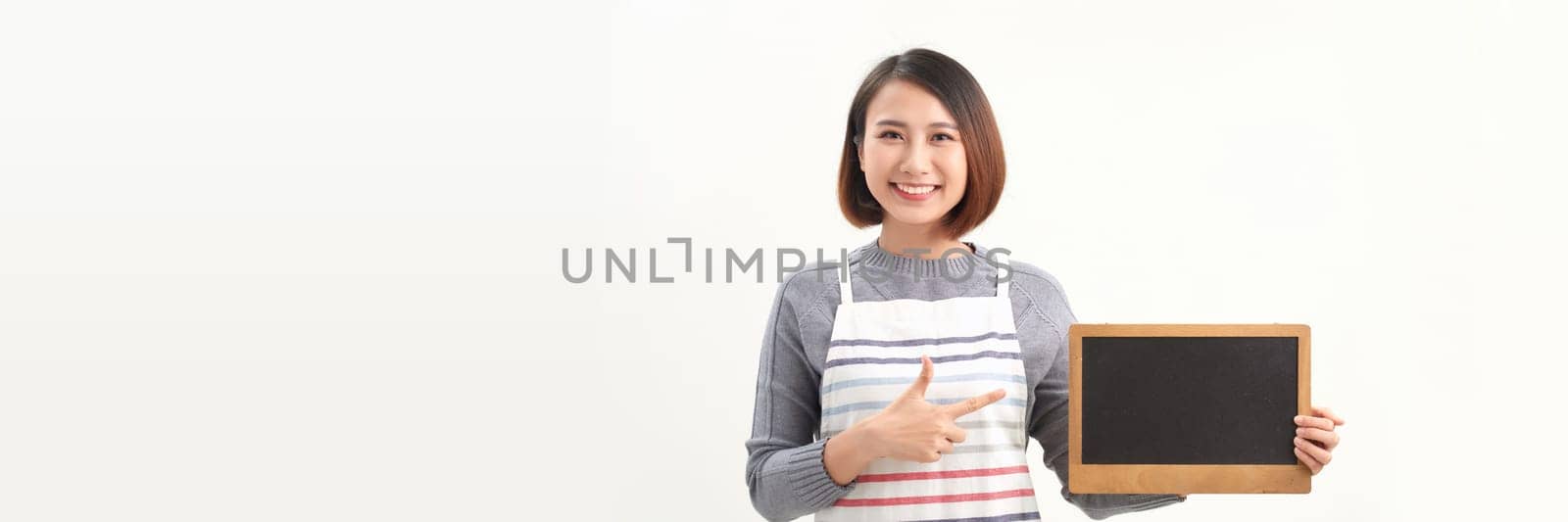 Waitress holding at empty board and looking at camera while standing on white banner background.
