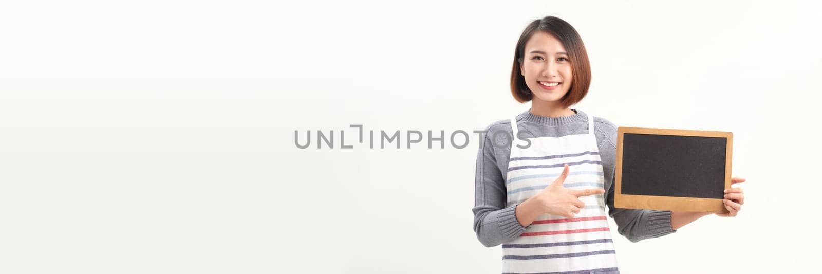 Beautiful woman in barista apron holding empty blackboard on white banner background  by makidotvn