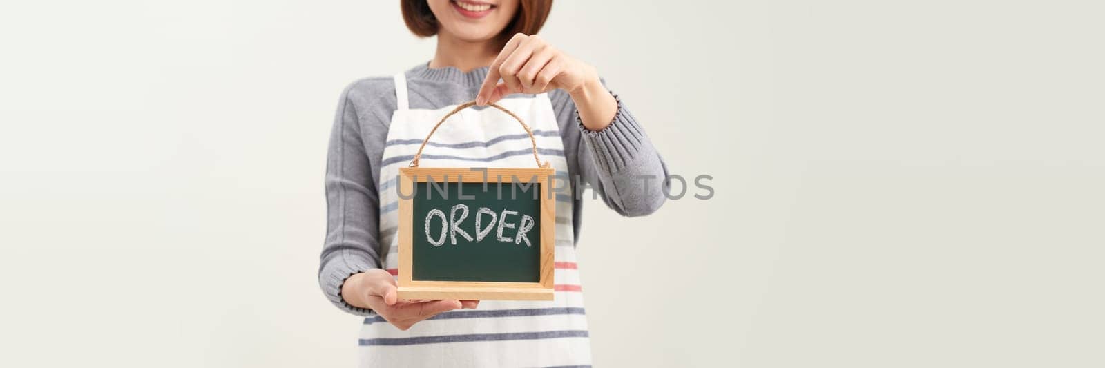  Hand of female entrepreneur with apron holding billboard, label or poster for ORDER by makidotvn