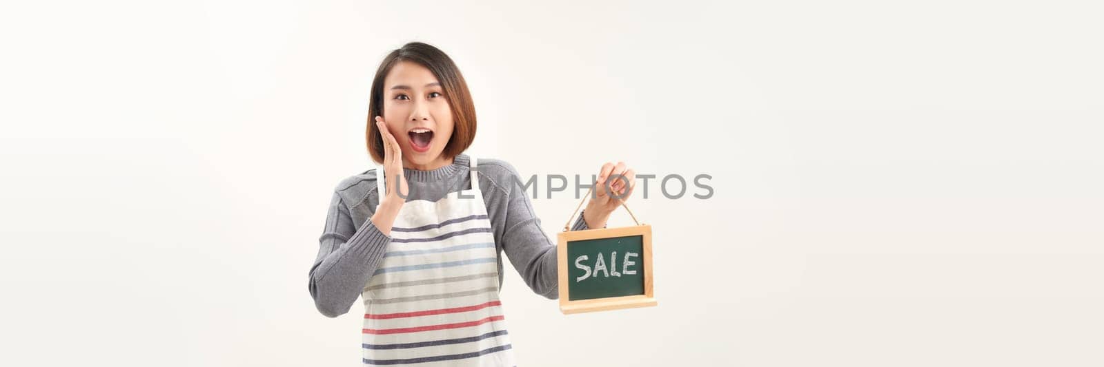 Young woman shop owner, wearing apron holding SALE word banner by makidotvn