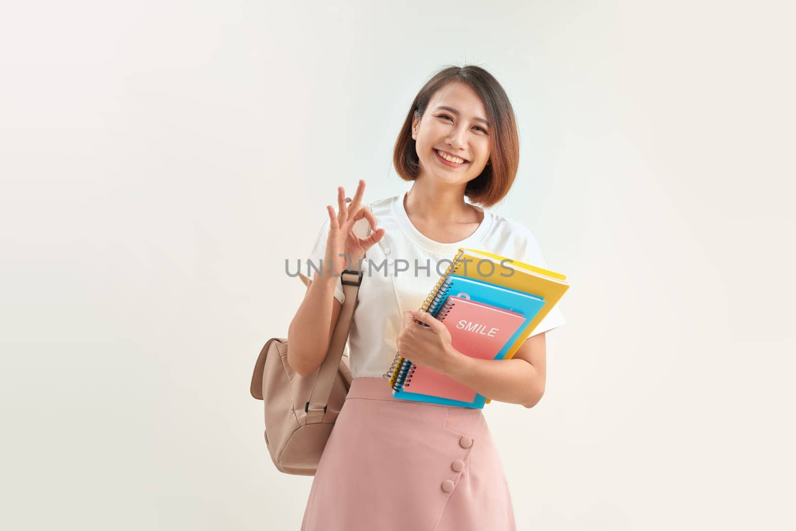 Cute student woman with backpack holds some documents and books over white background