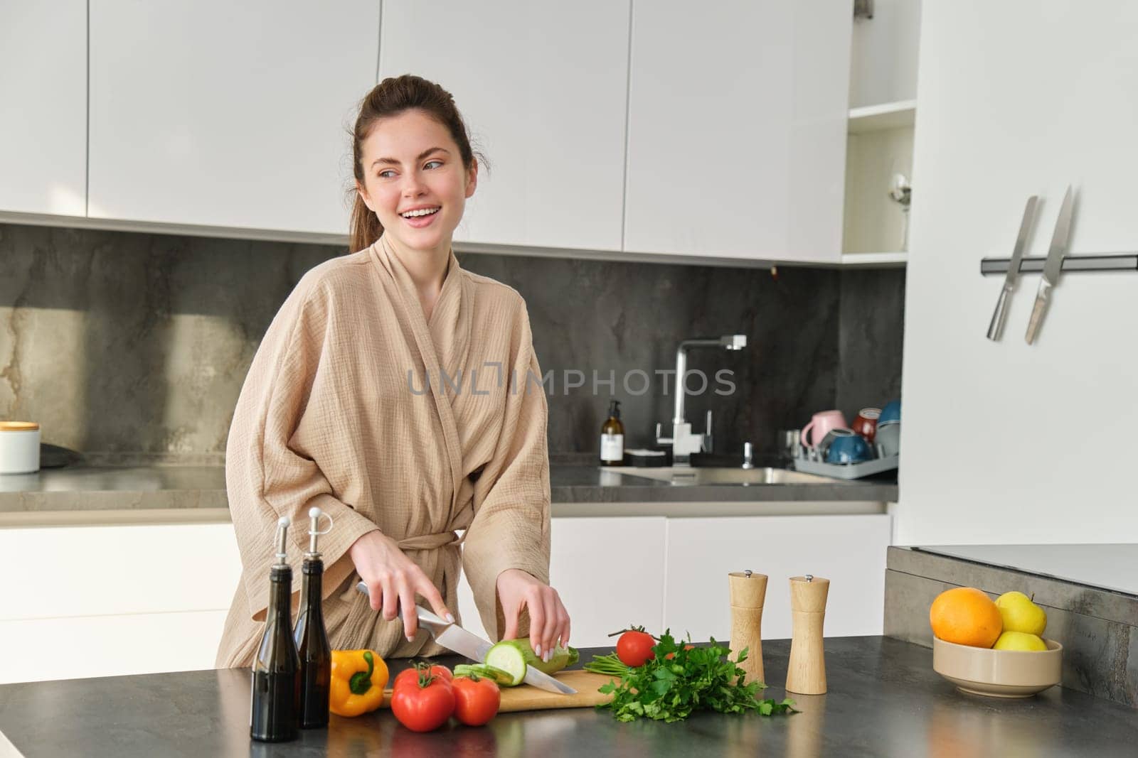Portrait of happy woman chopping vegetables on board, standing in the kitchen, cooking meal for herself, healthy food, preparing delicious fresh salad and smiling.