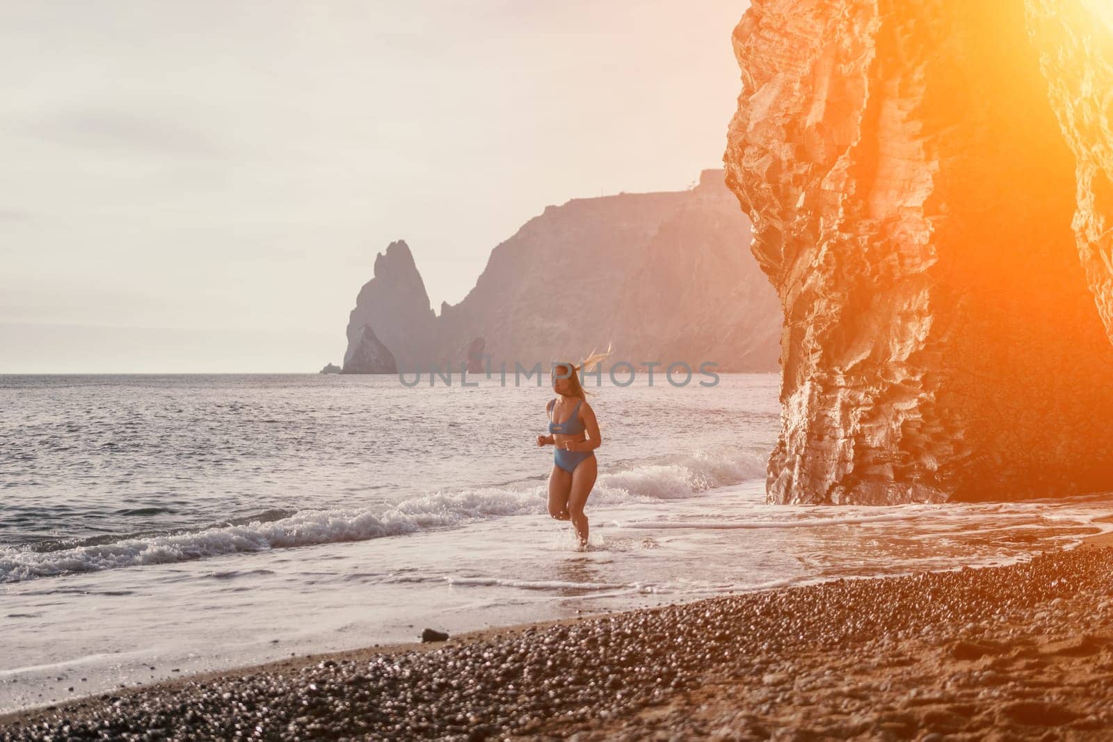 Running woman on a summer beach. A woman jogging on the beach at sunrise, with the soft light of the morning sun illuminating the sand and sea, evoking a sense of renewal, energy and health. by panophotograph