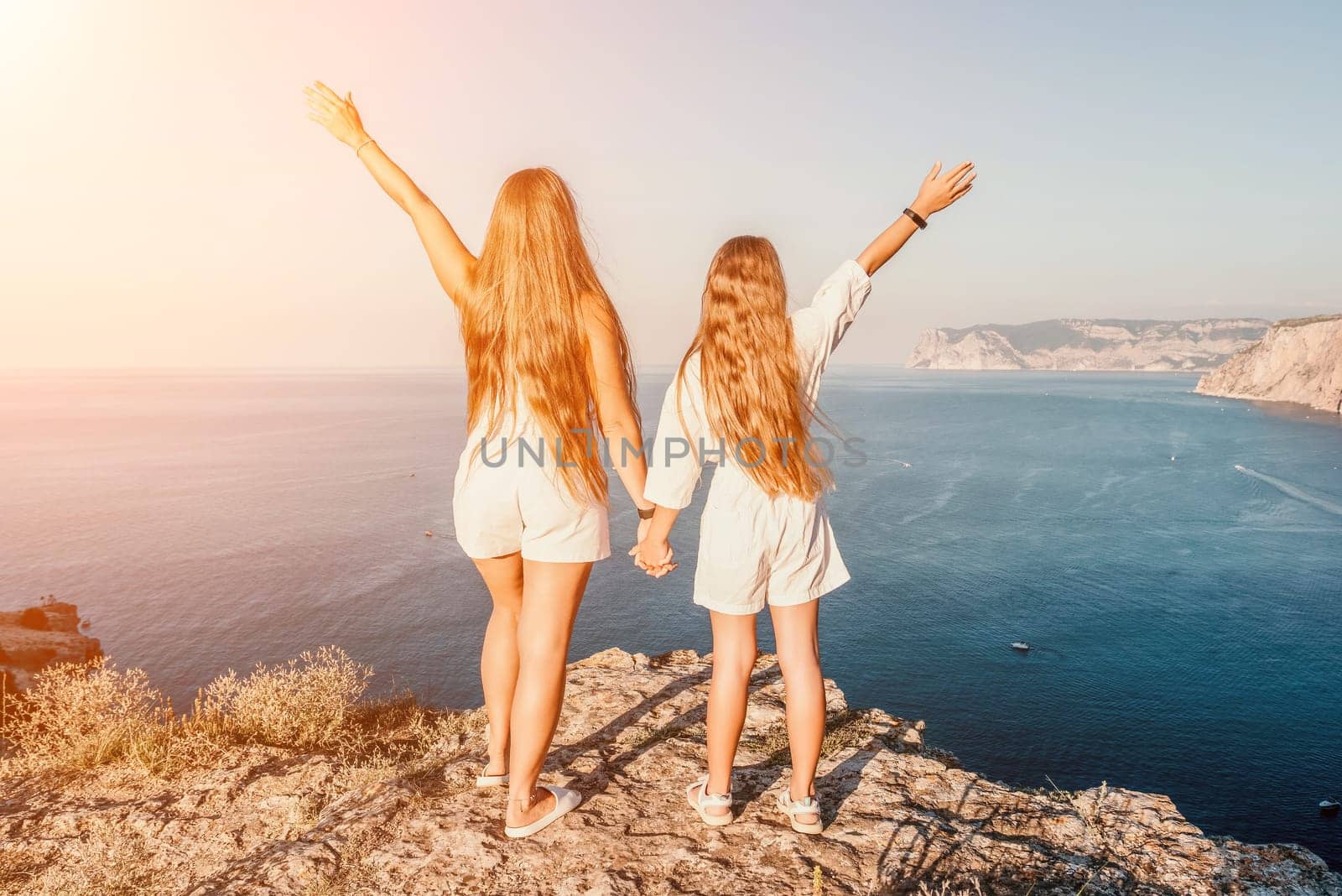 Close up portrait of mom and her teenage daughter hugging and smiling together over sunset sea view. Beautiful woman relaxing with her child.