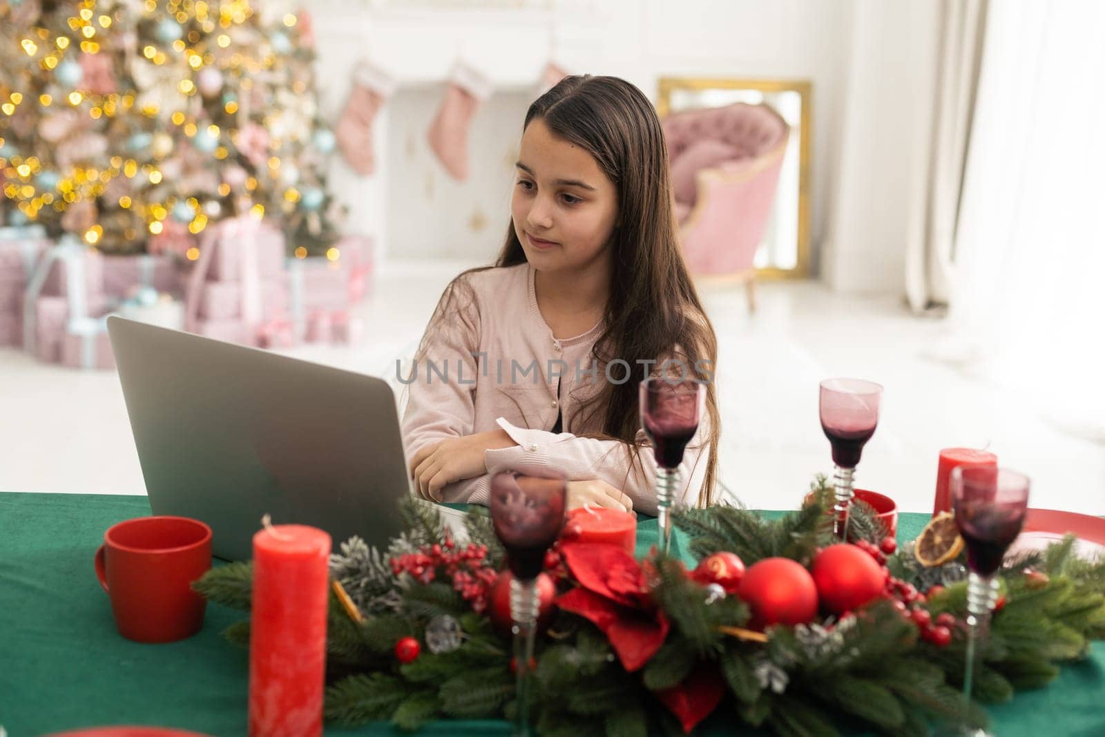 Christmas distance learning online education. Schoolgirl studying at home with laptop notebook and doing school homework. by Andelov13