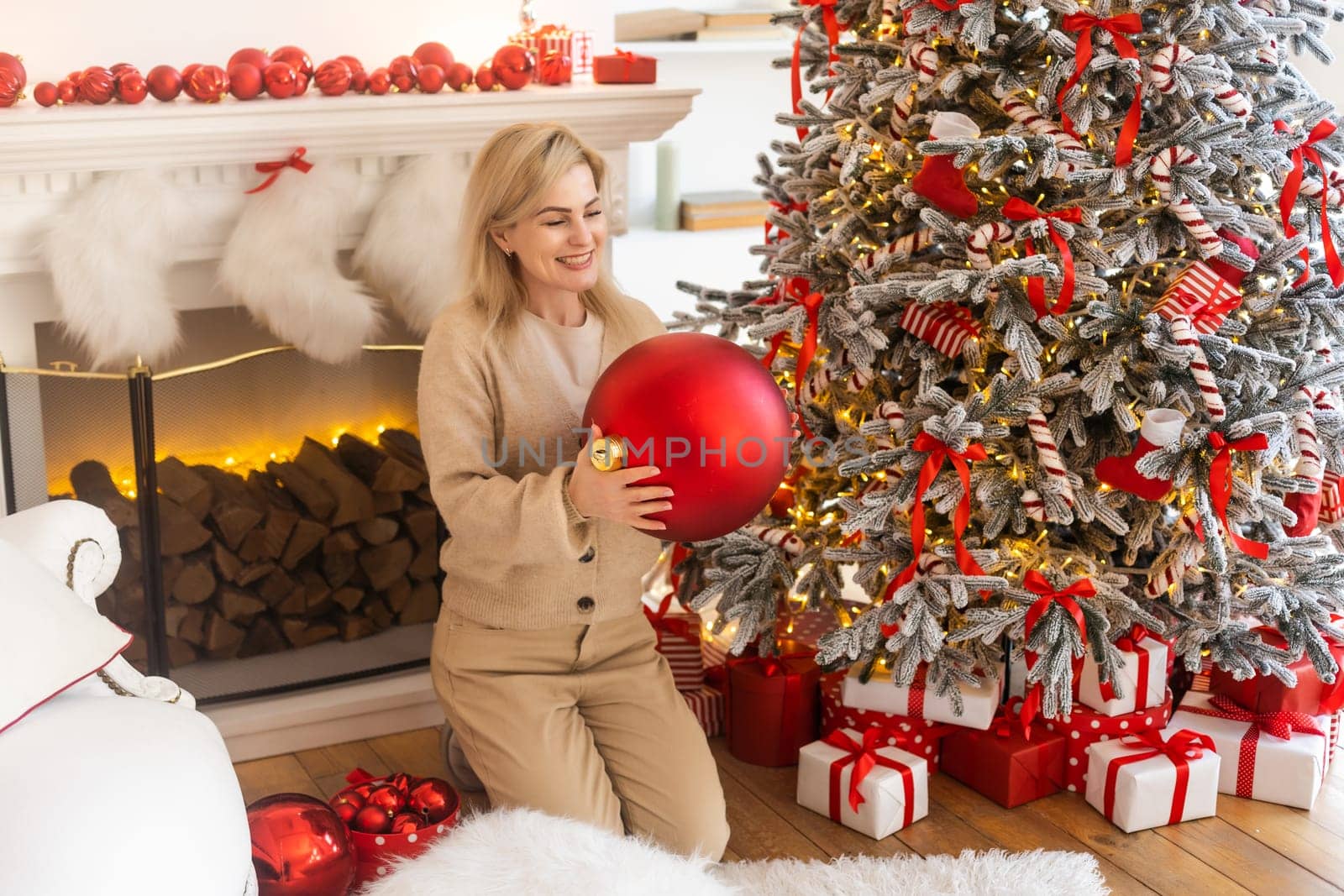 woman holding xmas ornament. girl decorate Christmas tree in a house. holiday celebration. season's greetings by Andelov13