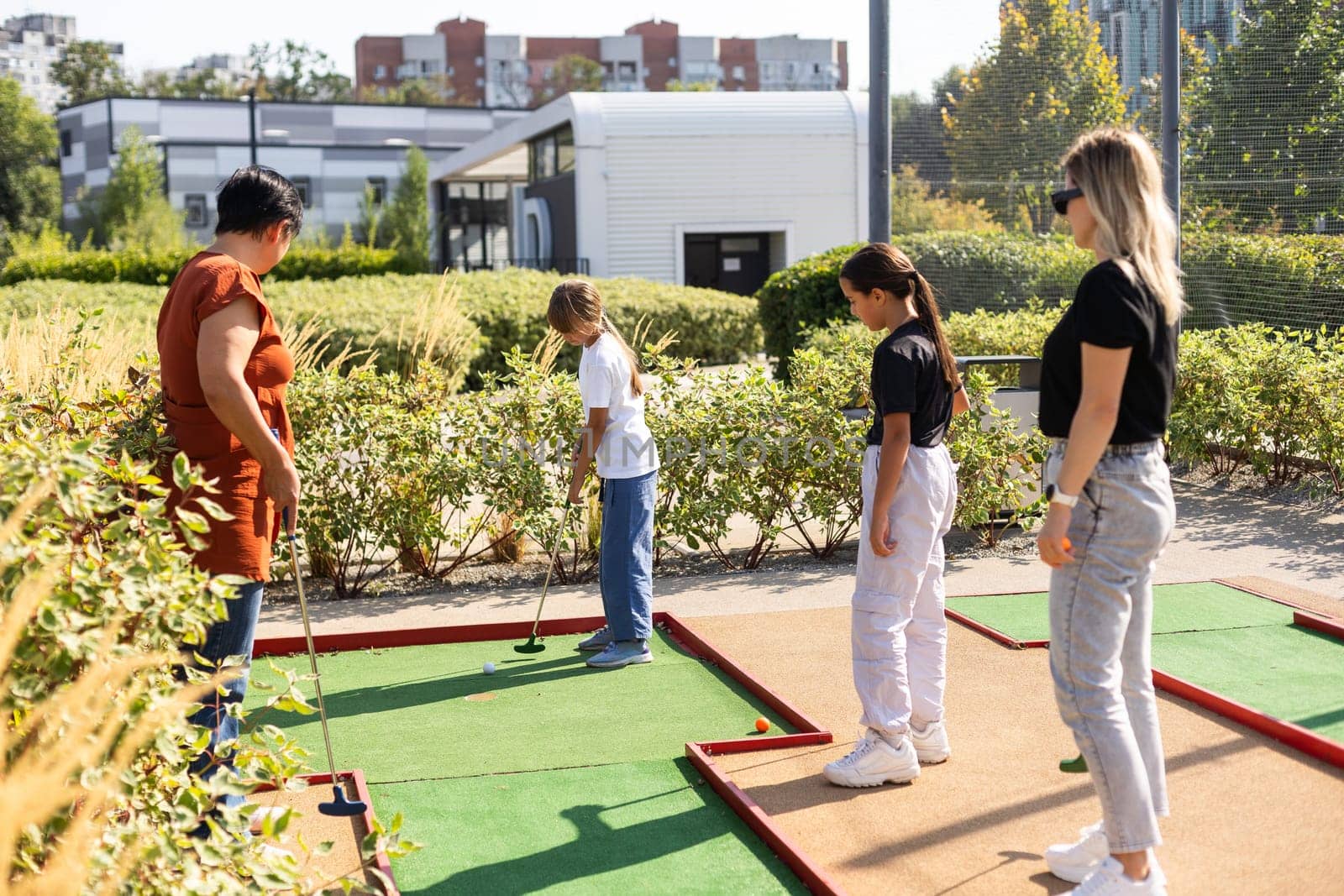 Mother and her little daughter practicing to hit the ball at the course. High quality photo
