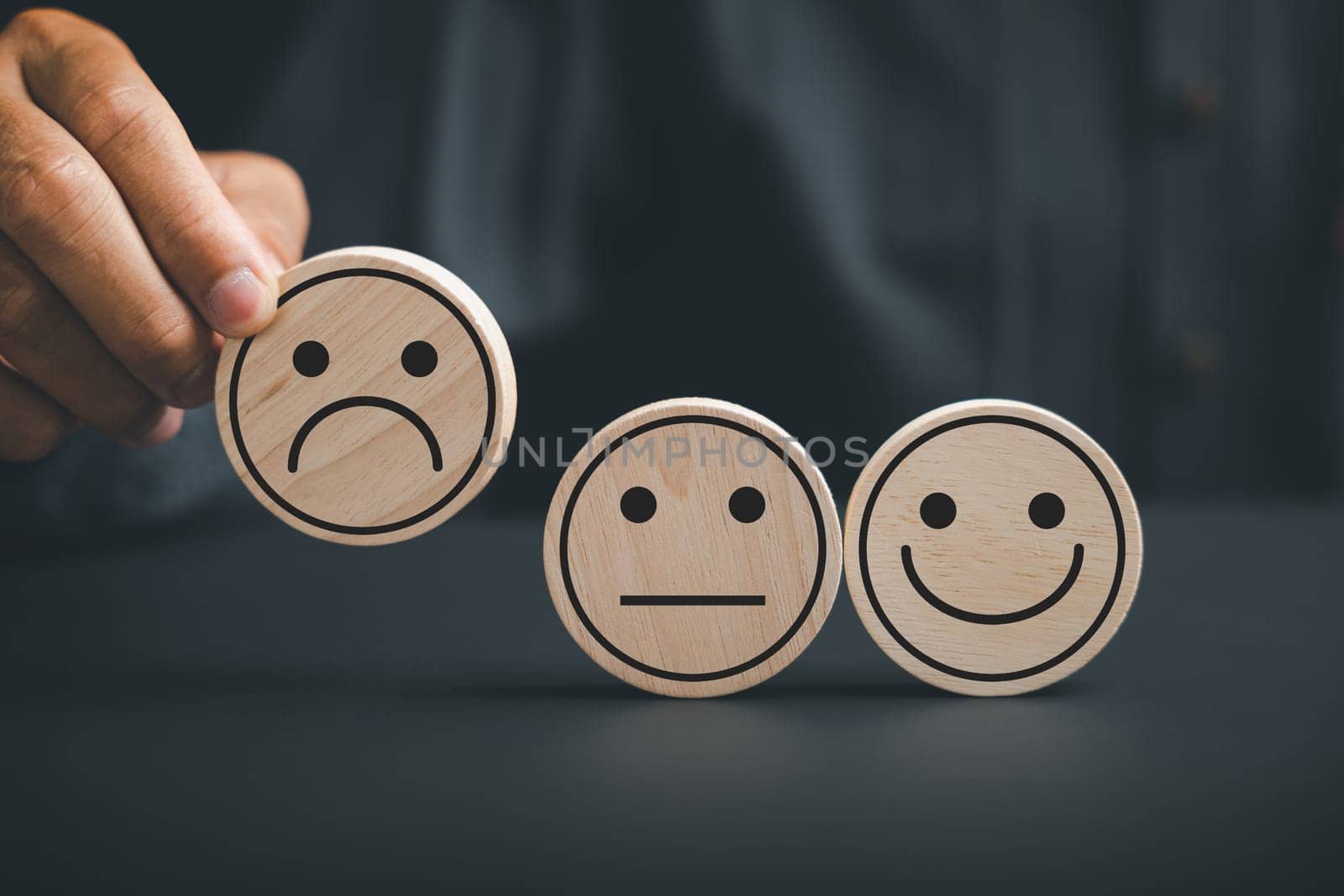 Unsatisfied customer holding frown icon on wooden circle by Sorapop