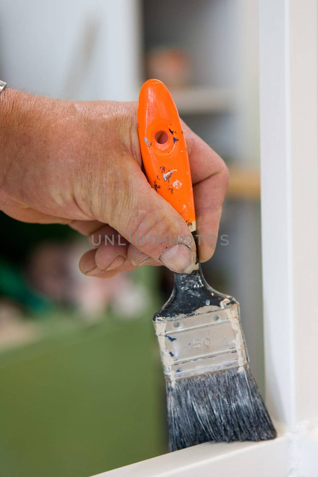 Close-up hand with brush in hand and painting a white frame