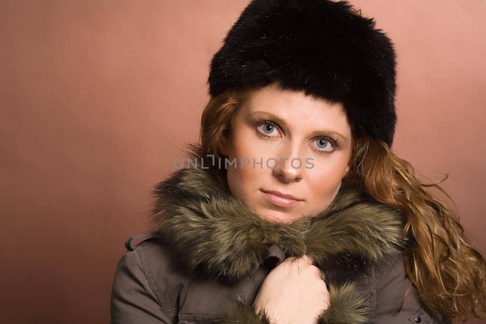 Young,attractive woman holding herself up warming jacket. Jacket with faux fur collar and faux fur hat.