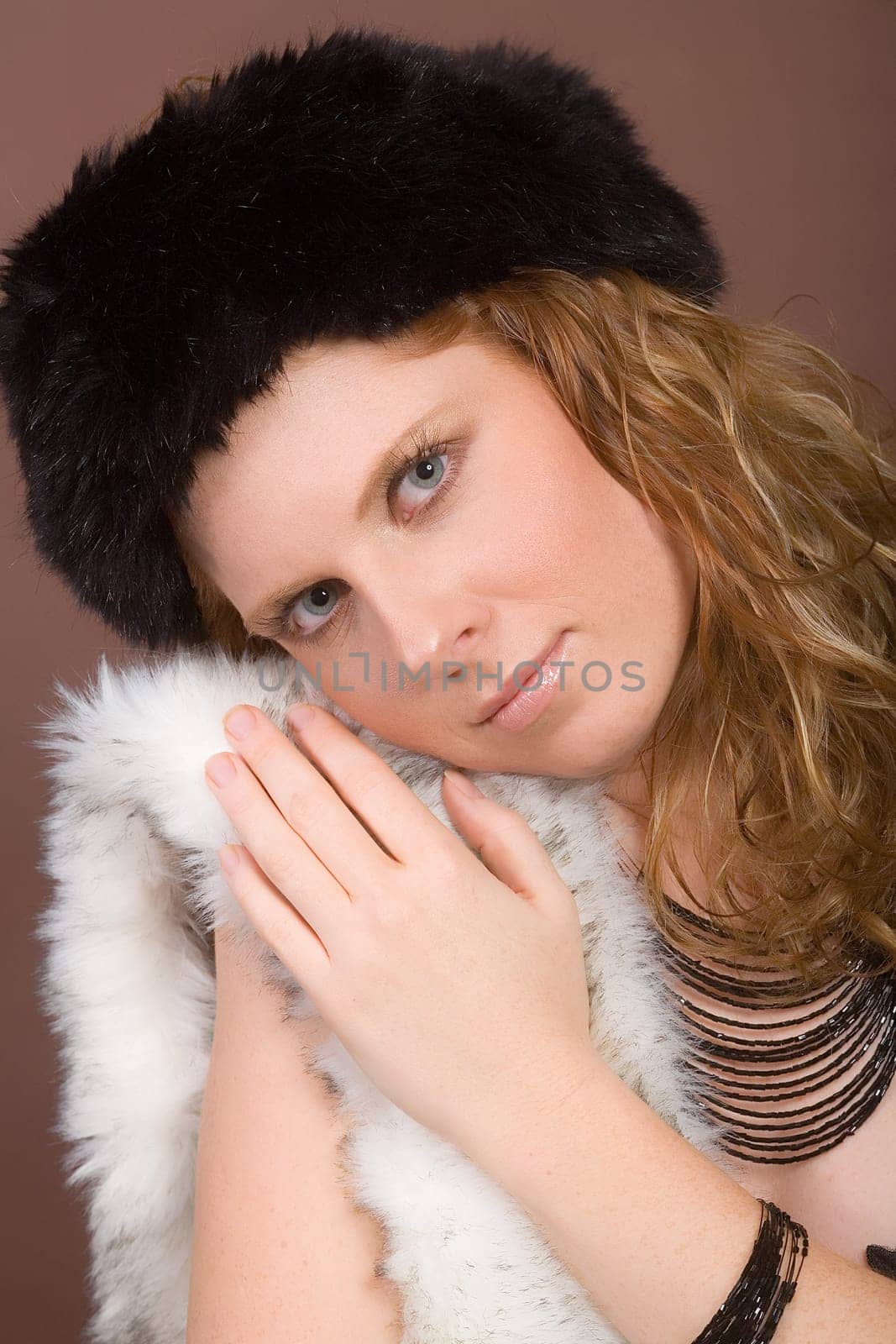 Young,attractive woman snuggles up to faux fur. On the head faux fur hat.
