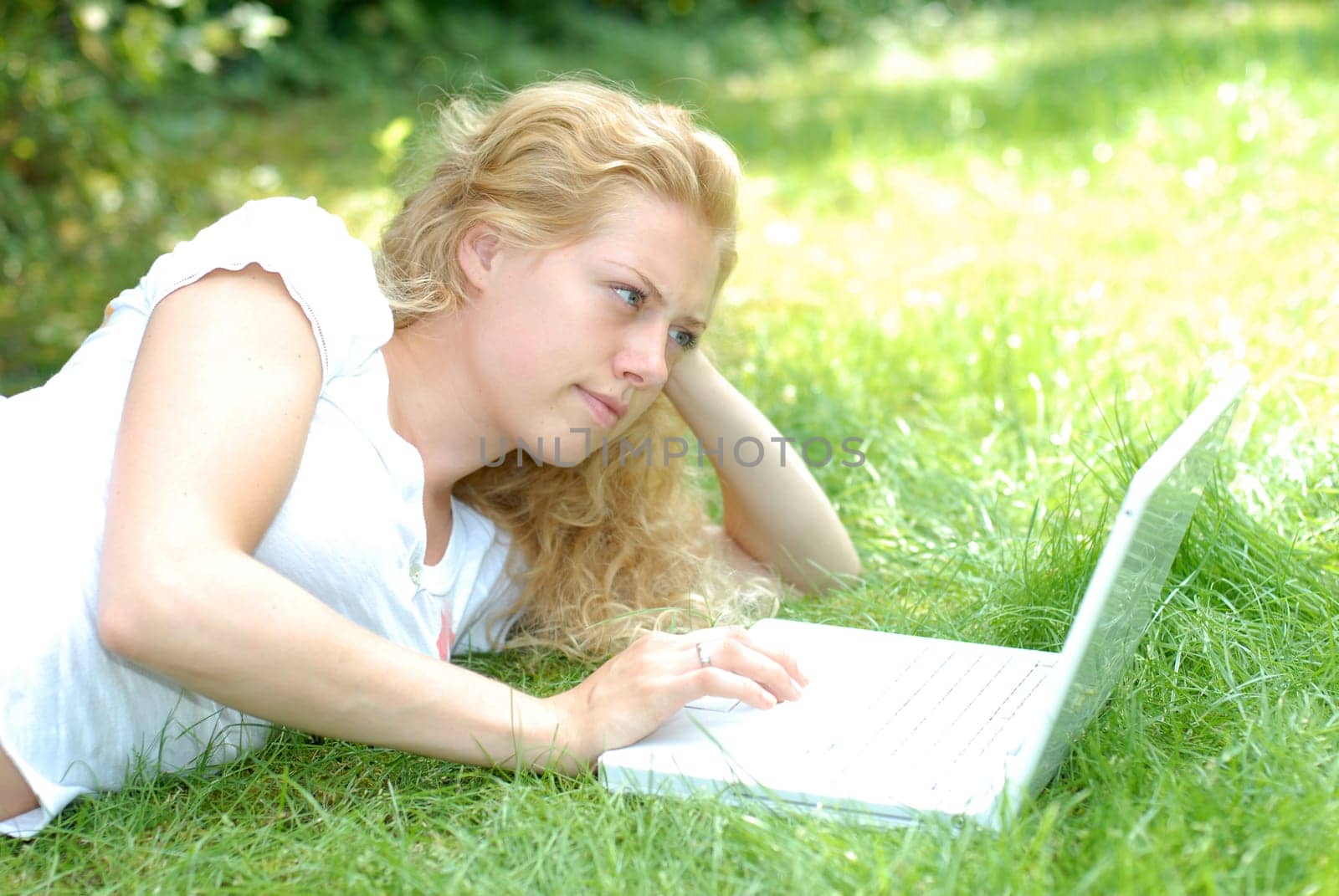 Young woman lying with laptop on meadow