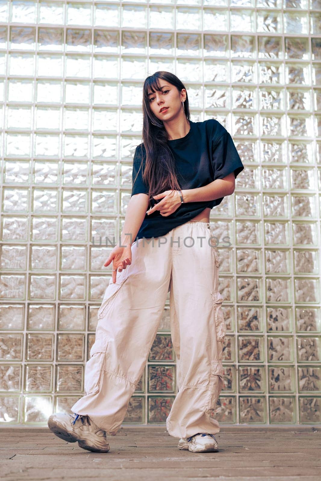 Dancer showcases fluid movements and style in a dynamic performance, set against a unique glass brick wall. The location adds a modern aesthetic to the choreography.