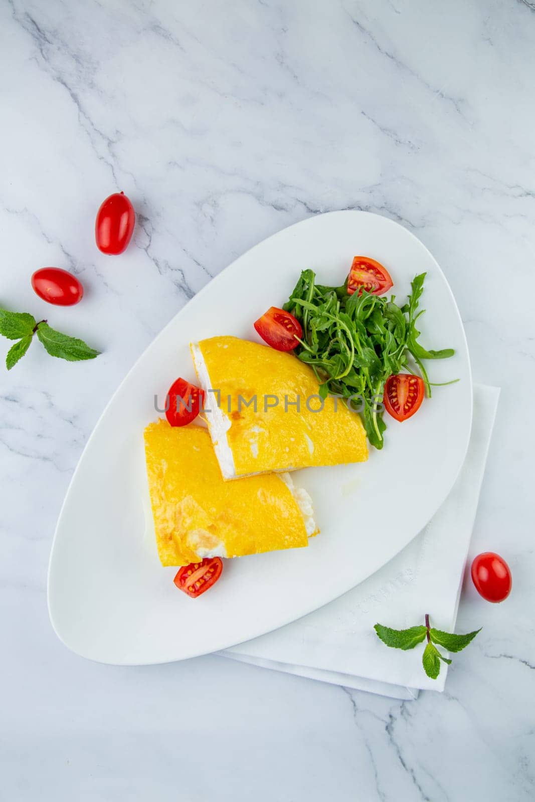 French tall omelette with arugula and cherry tomatoes top view by tewolf