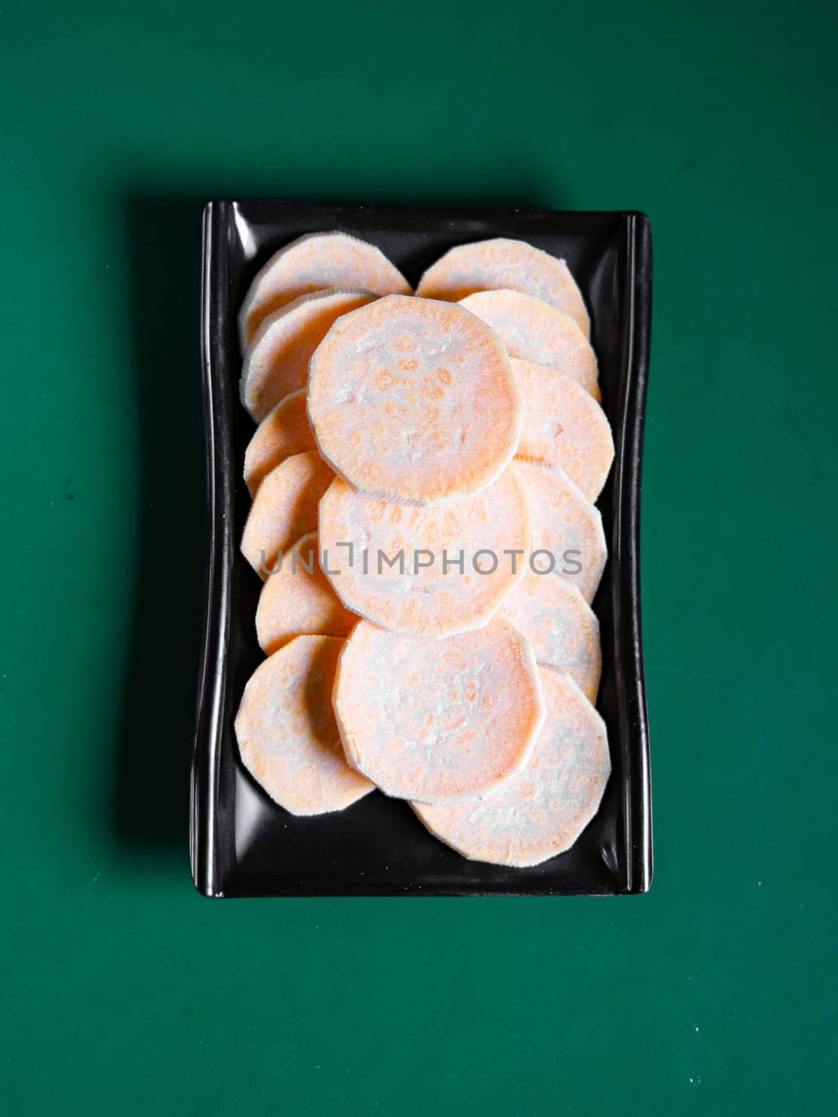 sweet potato slices on a black plate. View from above. Chinese cuisine, ingredient for hotpot by tewolf