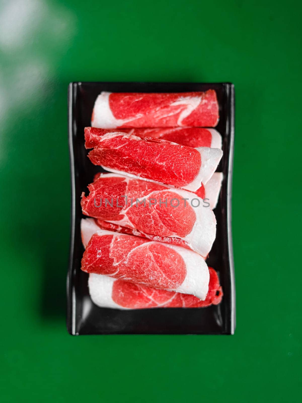 mutton slices on a black plate. View from above. Chinese cuisine, ingredient for hotpot by tewolf