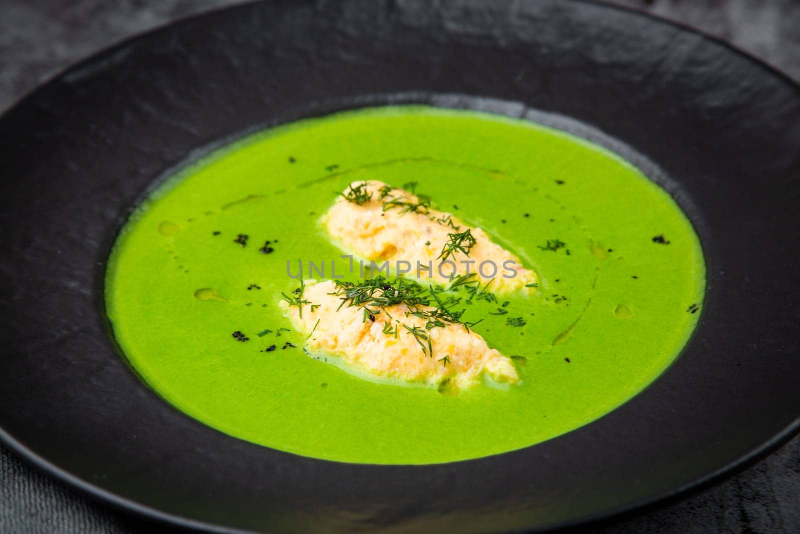 broccoli cream soup with pieces of chicken fillet on a dark background by tewolf