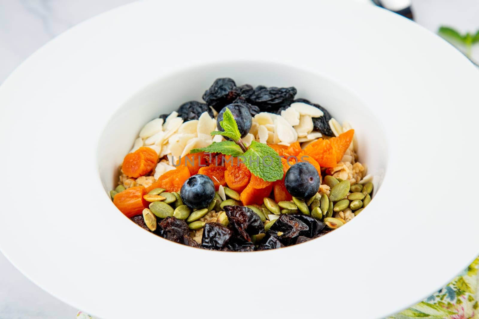 deep plate with cereals, berries, pistachios, dried apricots and raisins top view by tewolf