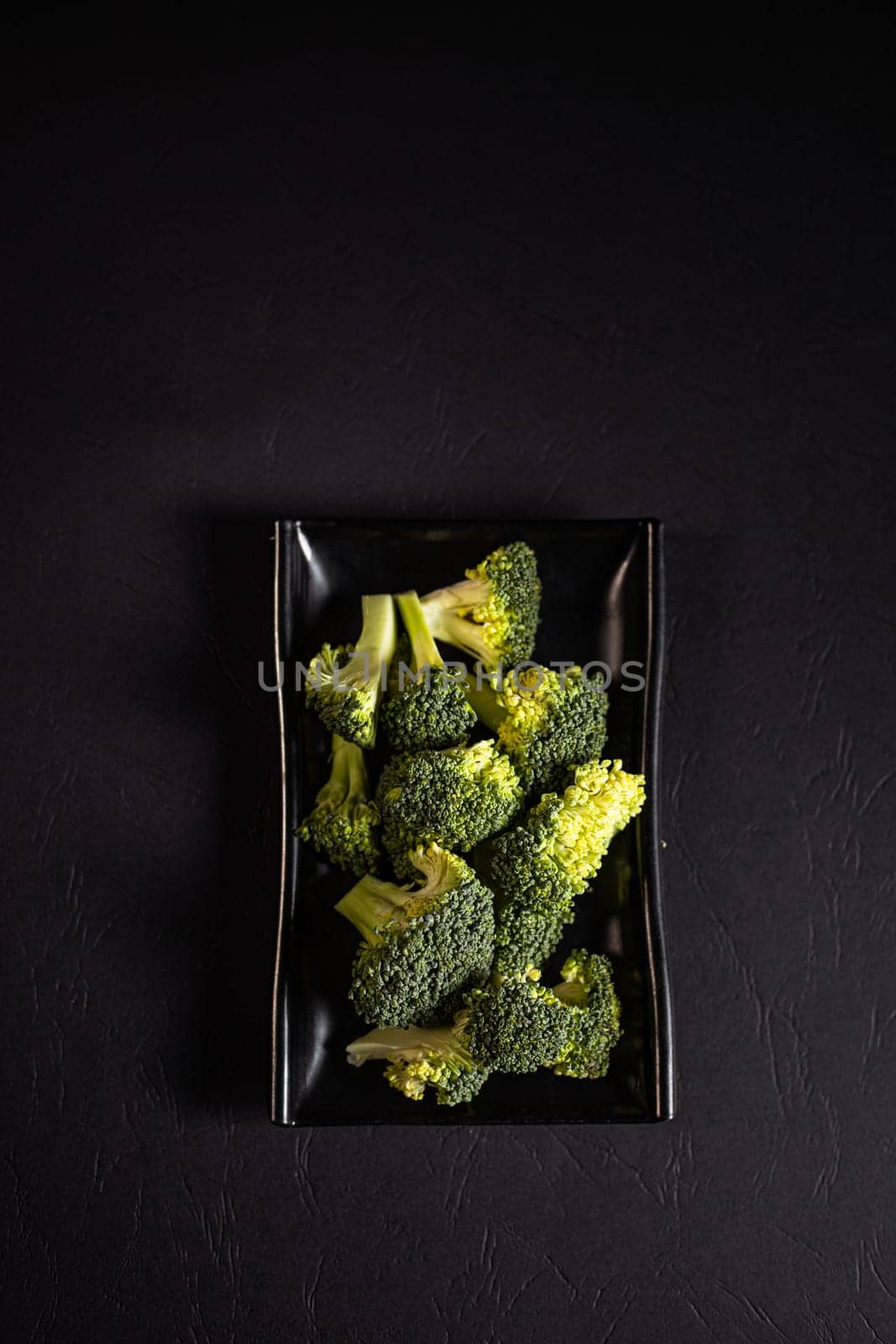 fresh and green broccoli on a black plate view from above by tewolf